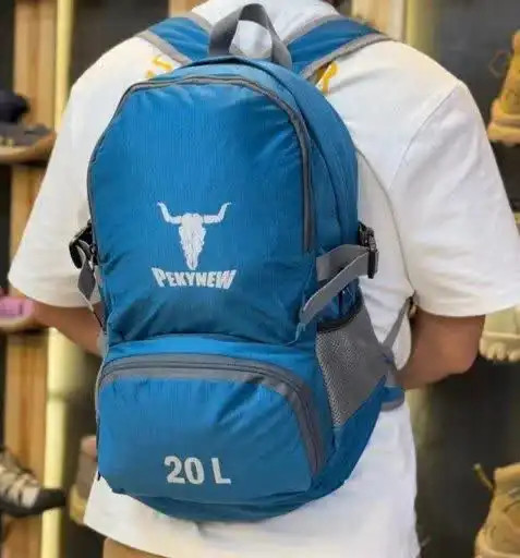 نمایش کولهپشتی مدل کلهگاوی PEKYNEW، رنگ آبی، حجم ۲۰ لیتر، با جیبهای جانبی و تسمههای تنظیم، عکاسی شده روی مدل در محیط فروشگاه.